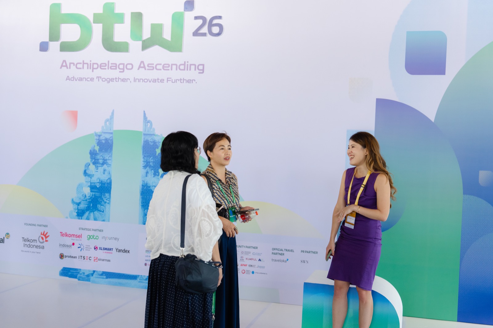 Claudia Natasia talking with attendees in front of the Bali Tech Week backdrop